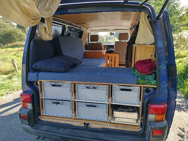 Interior view of the van - triptovantasia 06/2022 Interior view of Jo and Georg’s blue VW T4 van from triptovantasia, showing their minimalist bed setup and storage solutions during their vanlife journey.