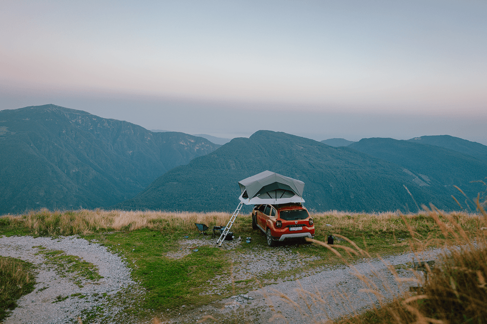 At sunset in the Balkan mountains, @hrvoje_juric’s Dacia Duster is parked on a remote ridge with a rooftop tent set up for the night, showing a peaceful moment of car camping, off grid living, and slow travel surrounded by wild nature.