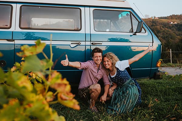 Hey, we're Thomas & Regina with our van "Edelweiss" - @edelweiss.on.the.road 06/2022 Thomas & Regina, from @edelweiss.on.the.road, pictured in the wine hills of Styria, Austria, wearing traditional Trachten clothing beside their VW T3 Vanagon "Edelweiss," capturing a moment at the beginning of their vanlife journey immersed in Austrian culture.