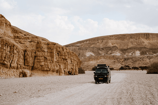 Mitch, our home on wheels, in the middle of the Arabian desert - @countless_roads 03/2023 Amy and Jeroen from @countless_roads drive their Mitsubishi L300 4x4 through a wide rocky desert valley surrounded by golden sandstone cliffs in the Arabian Peninsula. The scene reflects the spirit of overlanding and vanlife adventure, showcasing remote travel, exploration, and the rugged beauty of Saudi Arabia’s desert landscapes.