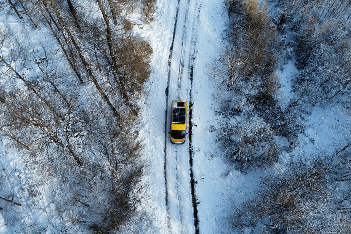 Our home on wheels managed to get us to the northernmost drivable point of mainland Europe in snow, ice, and freezing temperatures - @gary_and_sheila 06/2023 Aerial view of a bright yellow self converted Fiat Ducato camper van driving along a narrow snow covered forest road in winter, surrounded by frost covered trees and deep snow. The image captures remote winter vanlife, cold weather overlanding, and long term travel through northern landscapes during the journey of vanlife creators @gary_and_sheila.