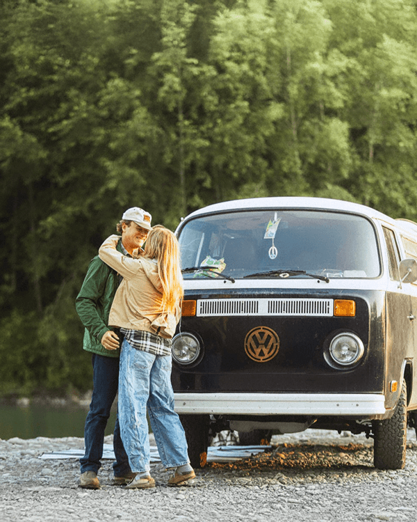 Peter & Tara with their 1978 VW T2 - @wanderingnwonder 06/2025 Peter and Tara of @wanderingnwonder share a joyful embrace in front of their restored black and white 1978 Volkswagen T2 Bus named Wonder, parked on a gravel riverbank surrounded by dense green forest. Captured during their vanlife journey across the USA, this moment reflects their adventurous spirit, deep connection, and love for slow travel and nature.