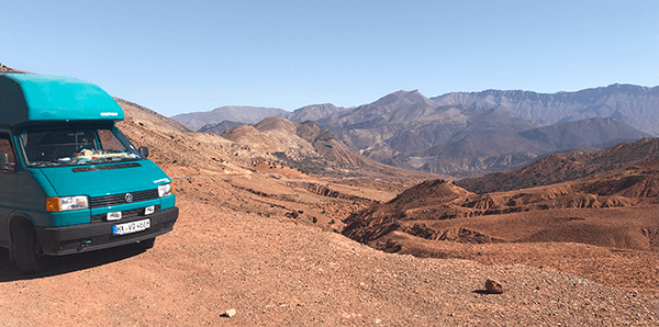 The Atlas mountains in Morocco are worth a visit - @leinen_los_zu_viert_ 06/2024 The teal Volkswagen T4 camper van from @leinen_los_zu_viert_ is parked on a rugged dirt road with a panoramic view of the Atlas Mountains in Morocco. The stunning landscape features rocky, arid terrain and distant mountain peaks under a clear blue sky, showcasing the adventurous spirit of their van life journey through North Africa.