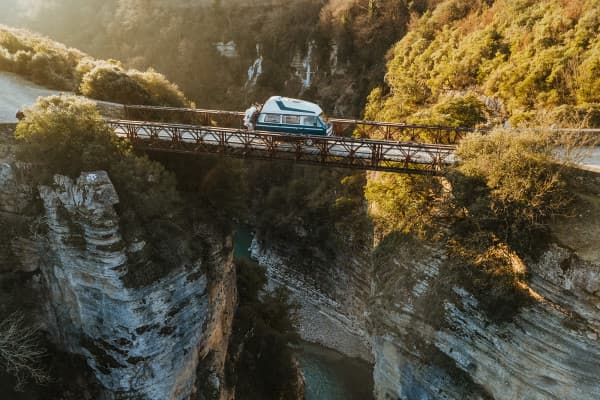 Driving Over the Magnificent Osum Canyon in Albania - @edelweiss.on.the.road 06/2022 @edelweiss.on.the.road is captured crossing a narrow, iron bridge high above the steep cliffs of Osum Canyon in Albania. This stunning image showcases their VW T3 Vanagon "Edelweiss" amidst the dramatic, rugged beauty of the canyon, reflecting their adventurous vanlife journey through the breathtaking landscapes of the Balkans.