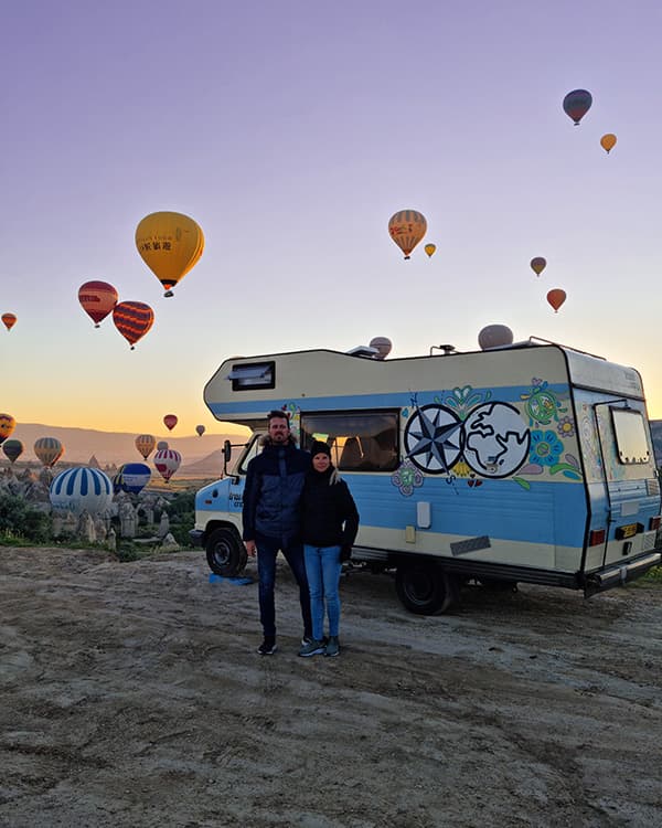 Renée, Joris & their camper Otto in Cappadocia, Türkiye - @travelcrazy.nl 09/2022 Renée and Joris from @travelcrazy.nl with their colorful camper van Otto in Cappadocia, Türkiye, surrounded by stunning rock formations and hot air balloons at sunrise, capturing the essence of van life adventures.
