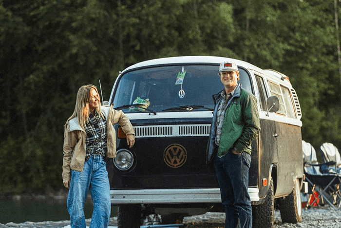 We're Peter and Tara - @wanderingnwonder 06/2025 Peter and Tara of @wanderingnwonder stand smiling beside their restored 1978 Volkswagen Type 2 Bus, parked on a rocky riverside with forest in the background. Captured during their vanlife journey across the USA, this moment reflects their love for nature, slow travel, and life on the road.