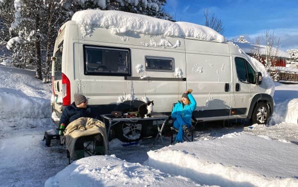 Mary, Peter and their cat Stefcia in snowy Norway - @travelvan 08/2021 Mary, Peter and their cat Stefcia enjoying a snowy winter day outside their converted campervan in Norway. The van is covered in snow, highlighting the adventurous spirit of winter van life in the Arctic.