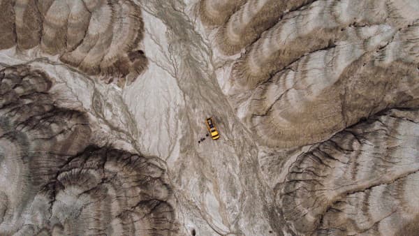 Areal view of Morris, a Mercedes-Benz Vario 816D camper in a dramatic landscape - @our_orbit_vanlife 07/2024 Aerial view of a yellow Mercedes Vario 816D camper van from @our_orbit_vanlife parked in a dramatic, rugged landscape with eroded rock formations. The van is situated in the center of the image, highlighting the stark contrast between the bright vehicle and the earthy tones of the surrounding terrain, showcasing the adventurous spirit of vanlife in remote, natural settings.