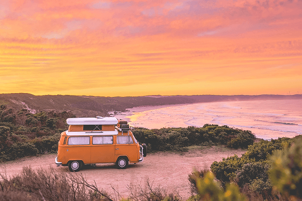 The journey has become our spirituality - @summerofseventyfive 12/2022 The summerofseventyfive family’s bright yellow 1975 Volkswagen Kombi camper van with its pop-top roof raised is parked on a coastal bluff overlooking a sweeping Australian beach at sunset. The sky glows in vivid shades of pink, orange, and purple, casting warm light over the ocean waves and rugged shoreline. Surrounded by native coastal vegetation, the scene captures the beauty of vanlife, remote camping, and the freedom of exploring Australia’s wild beaches.