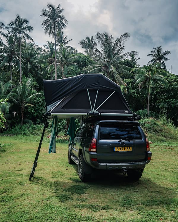 Wild camping under palm trees in Thailand - @char.is.far 01/2025 @char.is.far's Toyota 4Runner with a rooftop tent set up for wild camping in Thailand, surrounded by lush green grass and tall palm trees. The tropical setting highlights the serene and adventurous spirit of their overlanding journey from Europe to Asia. This peaceful campsite showcases their exploration of Thailand's natural beauty.